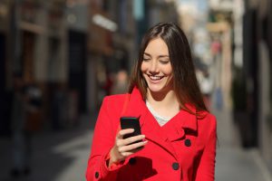 Woman using a smart phone while walk in the street